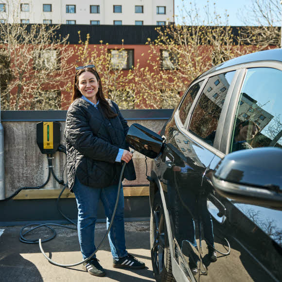 Kvinna sätter laddningskabel i elbil