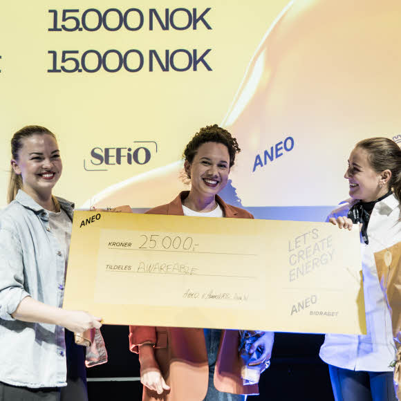 En gruppe kvinner som holder en stor sjekk der Aneo-Bidraget sponset