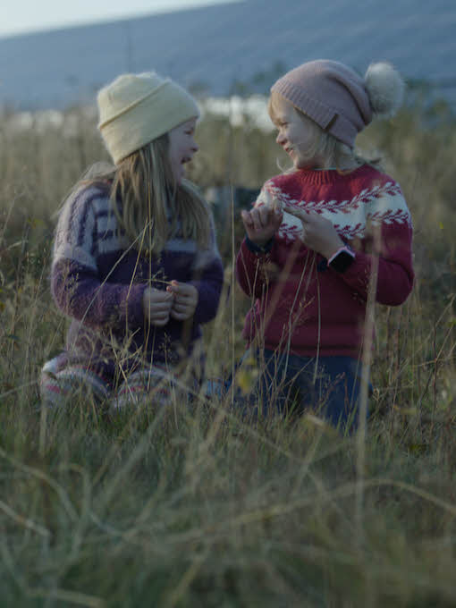 Two girls sitting in a field in front of sun panels