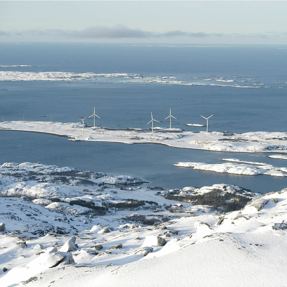 A body of water with a mountain in the snow and windmills