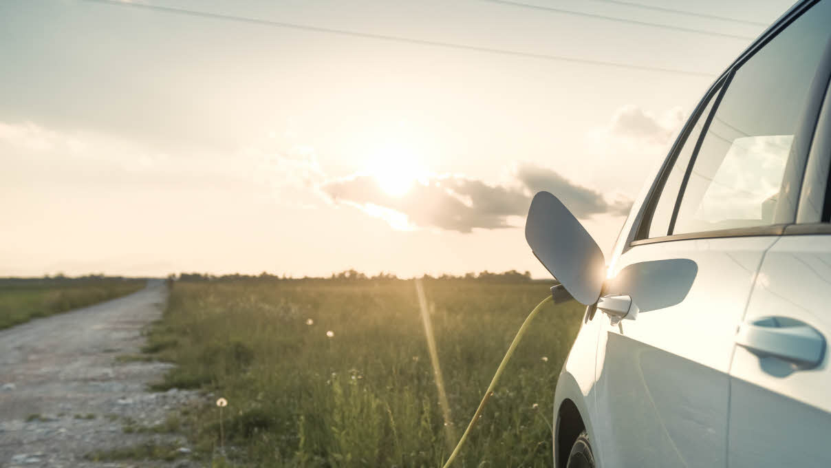Elektrisk bil lader i solnedgang 